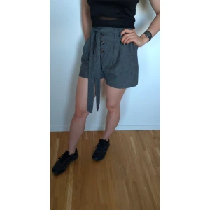 High waist shorts - Gråa shorts med hög midja. Passar perfekt för en lite mer elegant look för sommaren 👀 icke-stretchiga, inga fickor. Köpta för ung. 2 år sen, aldrig använda, så i nyskick. Säljer då dem inte kommer till användning. 