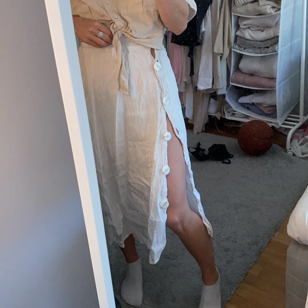 Säljer denna vita kjol, det är knappar på sidan som man kan välja att ha knäppta elr mod slitts, perfekt strandkjol! Stolek xs:). Kjolar.