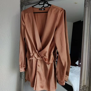 Playsuit Boohoo - En superfin playsuit från Boohoo, köpt på sellpy men aldrig använt den då den är lite stor i bysten men ser så sjukt bra ut med ett snyggt linne/bh under😍 Storlek 36! Inga defekter vad jag kan se, den är i väldigt fint skick 🤍🤍 Roseguld/brun färg 🤎