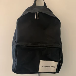 Calvin Klein ryggsäck - Svart Calvin Klein ryggsäck med vit logo, använd ett fåtal gånger.