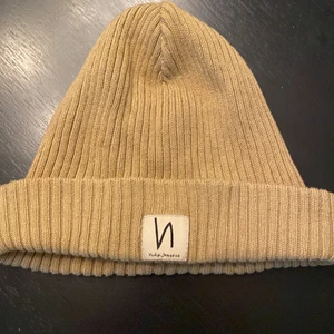 Nudie mössa - Beige mössa från Nudie jeans. Stl one size. Modellen är kort så ingen baggy mössa. 