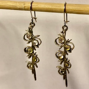 Handgjorda örhängen i glas och silver  - Unika örhängen, handgjorda i silver och glaspärlor som skiftar i silver och guld. Örkrokarna går att stänga, bildar en ögla som gör att man inte riskerar att tappa dem.