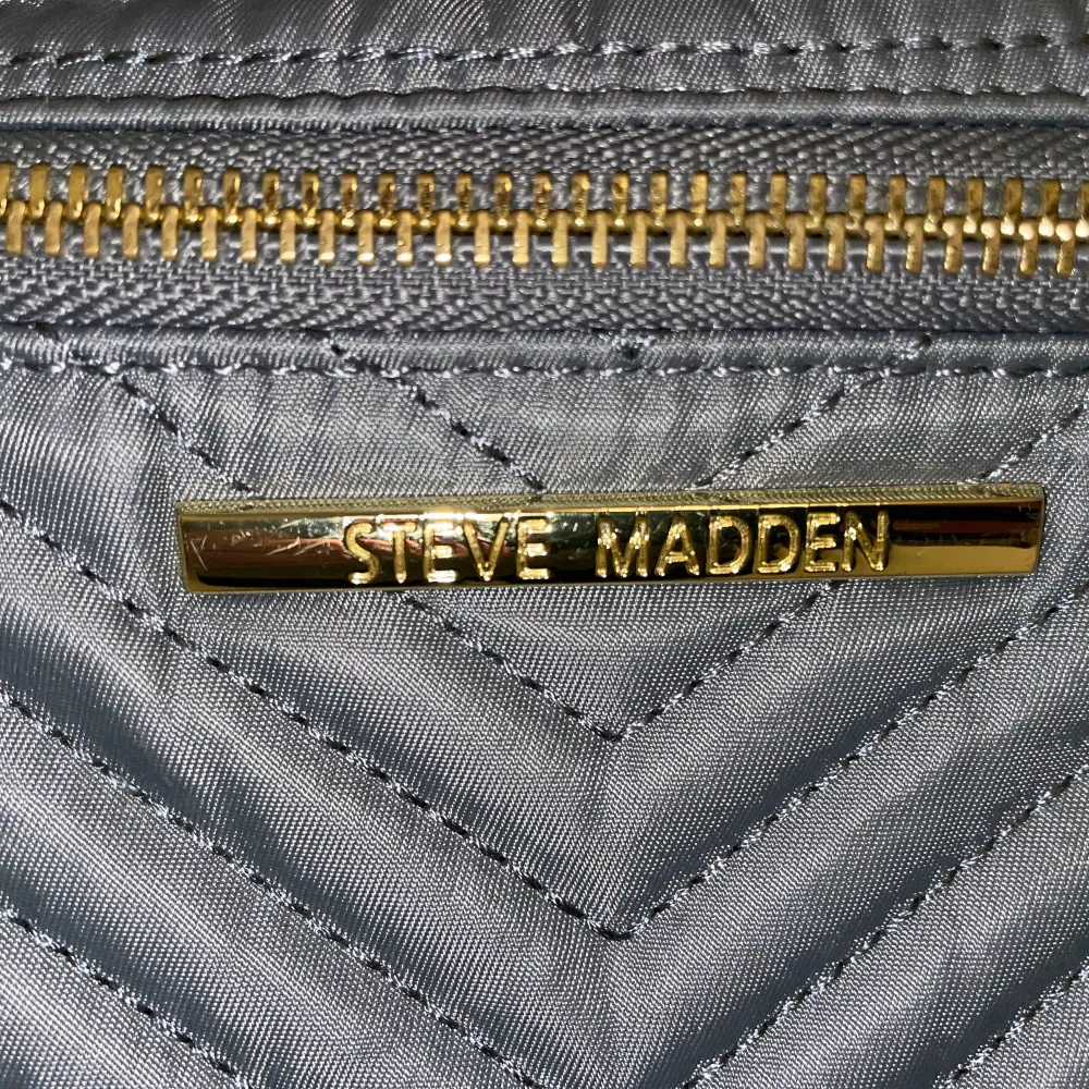 En grå Steve madden väska, (ÄKTA) men köpt i USA för ca 2 år sedan. Använd några gånger men har mest legat i min garderob💓 Den har någon jätte liten fläck där uppe, knappt synbar. Köpt för 1200💖. Väskor.