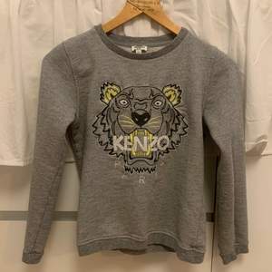 Grå sweatshirt från Kenzo, med gula och glittriga detaljer. Egentligen från Kenzo Kids avdelningen men passar XS. Använd mycket men utan synliga slitage,  kvaliteten är 10/10! 