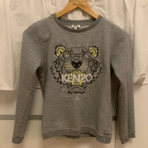 Kenzo Sweatshirt - Grå sweatshirt från Kenzo, med gula och glittriga detaljer. Egentligen från Kenzo Kids avdelningen men passar XS. Använd mycket men utan synliga slitage,  kvaliteten är 10/10! 