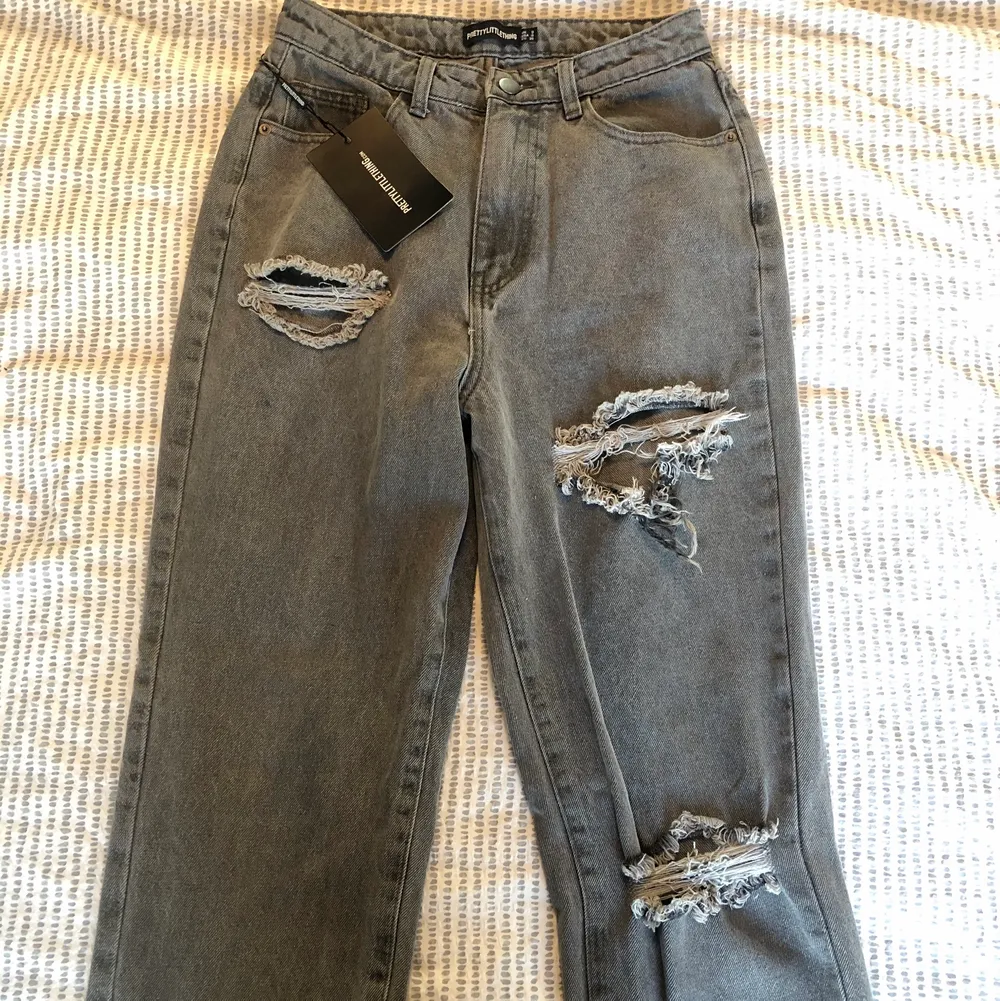 Säljer dessa as snygga gråa jeans med slitningar från PrettyLittleThing, de är i storlek 8 UK-size (ca 36-38). Köptes här på Plick men är aldrig använda med prislappen kvar! Tyvärr var de lite för stora och långa på mig som är 160cm, skulle gissa på att de hade varit bra i längden på någon som är runt 165cm+, annars kan man bara klippa dem lite! För fler frågor kontakta mig! Köparen står för frakt 💓. Jeans & Byxor.