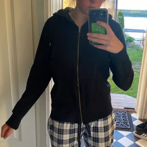Svart hoodie - Jag säljer en svart basic hoodie med dragskedja. Den har slitsar i armarna. Jättebekväm och passar till allt. I bra skick och inte använd mycket. I storlek M men skulle säga att den sitter bra på S också.