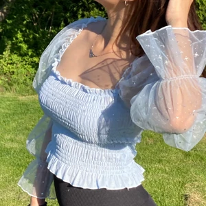 Puffärmad blus - Blåfärgad mesh med silvriga stjärndetaljer på armarna, stretchigt + ribbat material. Stolek S, nyskick och oanvänd.