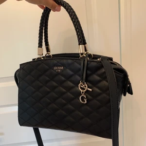 Väska - Säljer denna superfina väska från Guess i modellen ”penelope”. Använd ett få antal gånger utan några slitningar alls! Rymlig med flera fack på insidan och perfekt till vardags/skolan, 30cm x 15cm x 20cm. Köpt på väskcentrum så den är såklart äkta (går att bevisa mha produktnummret som finns på insidan). Köpte den för ca 1500kr!💕