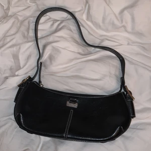 Väska - Väska i svart läderimitation, jättebra skick. Vita kontrast sömmar och justerbar längd. Rymligare än vad den ser ut :)