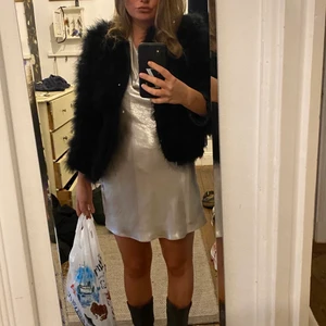 Kort klänning - Kort skimrig silverfärgad klänning, som dessutom är låg i ryggen! Den har knytband i nacken och går därför att justera!