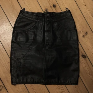 Läderkjol - Äkta läderkjol från 70/80-talet (min mammas gamla). Eftersom kjolen är i äkta läder är den lite ”stel” i jämförelse med läderimitation, sitter fortfarande sjukt snyggt dock - speciellt med tanke på att du kan knyta den så tight du vill ha den i midjan (bild 2). Strl 36 men funkar på mig som är 38! Skriv ett pris som känns rimligt för dig vid intresse! Hör av dig för fler bilder eller frågor!🤍