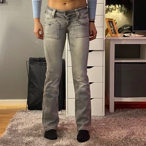 Lee cade Patch bootcut jeans - Grå bootcut jeans från Lee. Modellen är Cade Patch och har ett väldigt fint märke på baksidan med silver detaljer. Byxorna är i bra skick, nästan aldrig använda. Storlek W24 L31 ungefär XS. Modellen på bilden är 1,66 m