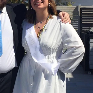 Vit klänning - Fin vit klänning i luftigt tyg. Använd under studentdagen, annars i nyskick. Puffiga ärmar med markerad midja. Mindre fläckar på insidan av klänningen som lätt försvinner i tvätten. Ger smickrande form på kroppen, passar M/L. 