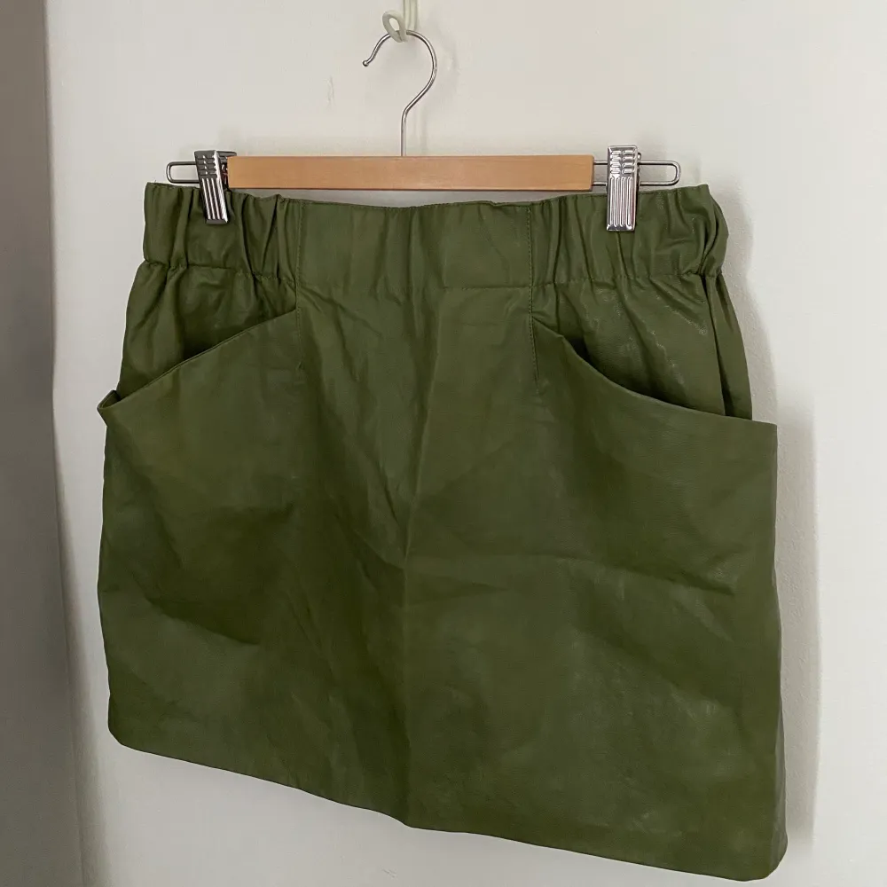 En jättefin grön kjol i skinnimitation från Zara. Kjolen är aldrig använd och är i storlek L och har två fickor framtill. Köparen står för frakten. . Kjolar.