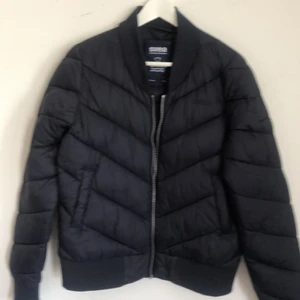 Svea dunjacka lätt . Stl L Marinblå/Svar - Dunjacka använd ca 3 ggr. Lätt dunjacka går att packa ner i väskan smidigt. Vid varmt väder. Är L Kärlek från Svea. Nr 10089600 i mkt fint skick. Väldigt mörk marinblå. Se bilder och bedöm lägger ut en puderrosa likadan snart. Mvh