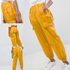 Gula parachute byxor - Coola gula fallskärmsbyxor samma variant Eleven bar säsong 03x02 32:40 i Stranger things! Stretchiga i midjan, fickor i sidan, avtagningsbarahängslen och åtdragning vid benen. Knappt använda.   Materialet är tunt och påminner om det på en regnjacka. 