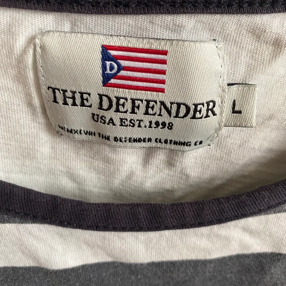 Randig T-shirt från The Defender. Herrmodell i strl L. Passar dock som en oversized S/M på mig. Använd endast 1-2 ggr.. T-shirts.