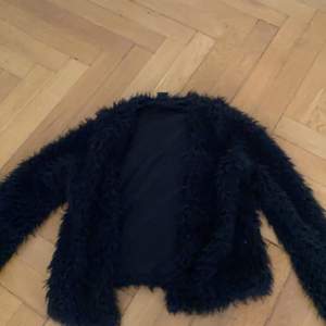 En svart fluffig jacka från Gina tricot i storlek S
