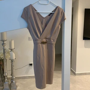 Beige klänning  - En beige klänning med guld detalj vid midjan