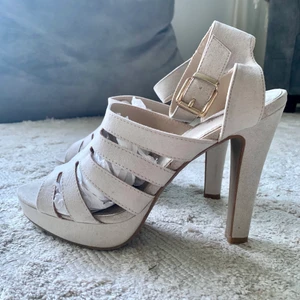 Helt nya klackar/ stl 39/ oanvända - Sommarens supersnygga sandaletter i beige mockaimitation. Läcker modell med breda remmar samt öppen tå. Hög klack, platåsula samt ankelrem med justerbar knäppning. Perfekt till festen! Klackhöjd 12 cm. Aldrig använda. Storlek 39. Skriv gärna för fler bilder :)