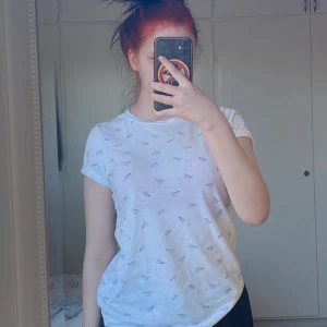 T-shirt, vit - Vit t-shirt med pappersflygplan på, sitter bra fick den av min syster men knappt använd av mig