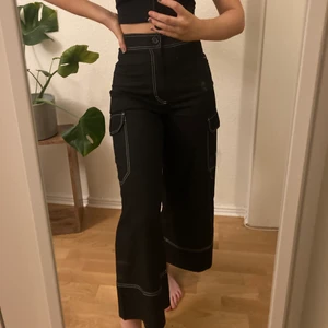 Höga cargobyxor  - Svarta cargobyxor från Monki. Vida, lite croppade ben och sitter tight i midjan. Supersköna och snygg passform!