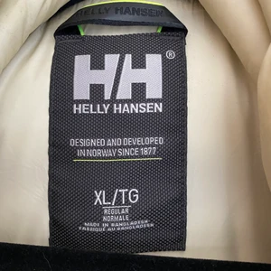 Helly Hansen dam dunjacka i beige  - Använd 1 månad. Inga märken eller tecken på att den har används. Storleken är dam XL.   Varmt fodrad vinterjacka för kvinnor från Helly Hansen. Med en lång, feminin design och fluffig huva för extra värme. Flera smarta fickor ger säker förvaring och uppvikbara reflexdetaljer ger ökad säkerhet i mörker. PFC-fri vattenavvisande behandling gör att regn och snö stöts bort och håller dig torr längre. Hi-Loft-fyllning värmer väl.