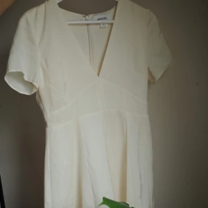 Ljus sommarklänning  - Benvit V-ringas klänning ifrån monki. I polyester-material. Väldigt sparsamt använd. Har en liten liten grå fläck (syns långt ner till vänster på andra bilden). Passar storlek xs/s. Säljes pga för liten. 