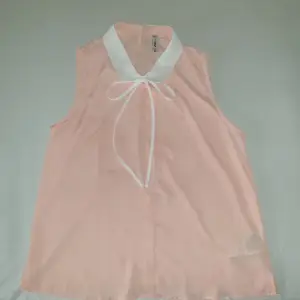 Genomskinligt rosa linne i storlek S med vit krage och vita band. 
