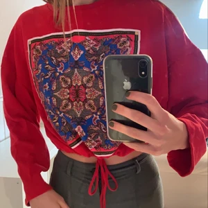 Croppad sweatshirt  - Säljer min klarröda croppade sweatshirt med ett annorlundra tryck på magen. Den har ett band nertill som du kan välja att spänna ifall att du vill att den ska sitta lite tightare i midjan. Köpare står för frakt.❤️