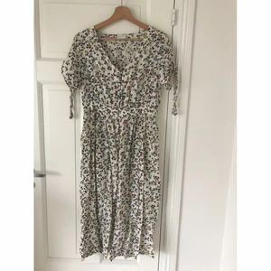 Fin blommig sommarklänning med kort ärm och knappar strl 36 - Fin blommig / bladmönstrad sommarklänning med kort ärm och knappar i strl 36, använd ett fåtal gånger så i fint skick. Sitter tightare runt midjan och slutar mellan vaden och ankeln på mig som är 169cm. Obs klänningen är ej struken på bilden.
