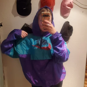 Windbreaker - Nu har du chansen att lägga vantarna på en unik windbreaker med retrovibbar! Reflekteras jättefränt i holographic i ljus! Texten sitter lite lös i kanterna men det hör till! Onesize och jättestor snygg luva
