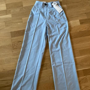 Kostymbyxor stl 34 - Ljusblåa kostymbyxor från Bershka. Aldrig använda, lappen kvar. Nypris 299 kr. Säljes pga att de tyvärr inte passar mig.