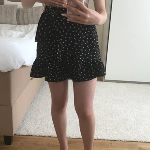 Svart blommig kjol i strl xxs/xs - Så fin svart kjol i blommigt mönster med volanger. Kjolen är aldrig använd.💖