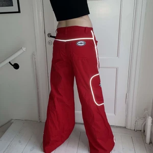 Röda byxor  - Ett par baggy röda byxor. Låga i midjan pösiga i benen. Reflex sömmar längst benen och fickan. Innerbenslängden: 86cm midjemått: 84 cm