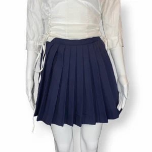 Kjol - Söt marinblå tenniskjol-liknande i fin kvalite! Inga fläckar eller hål finns, men lite upprivet där man stänger kjolen. Det syns inte när kjolen är stängd och används! Inget märke eller material finns. Ingen stretch. Mått -   Midjebredd 32cm, Längd 37cm.