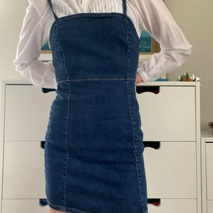 Mellanblå Kort Jeansklänning  - Mellanblå kort jeansklänning från Pull and Bear, stl S. Skönt, elastiskt material som formar sig efter kroppen: 98% bomull, 2% elastan. Perfekt till sommaren! 