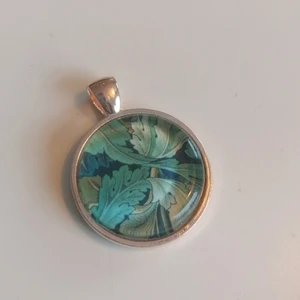 William Morris halssmycke - Halssmycke i silverfärgad metall och glas. Med motiv av William Morris. Nickelfritt. 25 mm i diameter. Budgivning! 