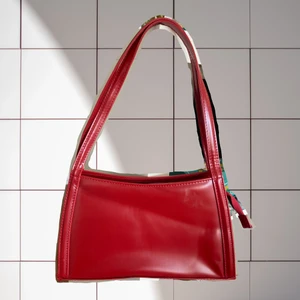 SNYGG handväska! Vinröd - Megasnygg handväska i vinröd färg. Mycket rymlig, stängs med dragkedja. Liten märkning på ena sidan, se sista bilden. Väskan har en innerficka med dragkedja. Väskan har lite klister från en gammal prislapp, men går antagligen att ta bort. Fri frakt.