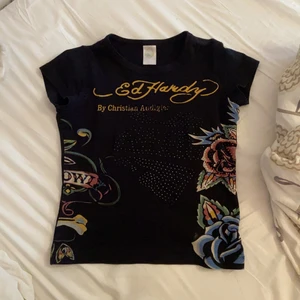 Ed Hardy tröja - Cool Ed Hardy babytee i bra skick!!❤️ Tryck både fram och bak+ rhinestones😇 köpt second hand så vet inte säkert om den är äkta, den har ett pyttelitet hål i bak, dma för bild! ❣️skriv privat för fler frågor<3 KÖP DIREKT: 300