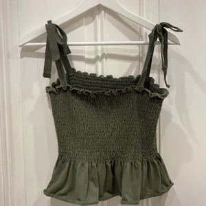 Smockad topp från H&M - Jättesöt smockad topp från H&M. Axelbanden går att knyta lite hur man vill. Kan även posta