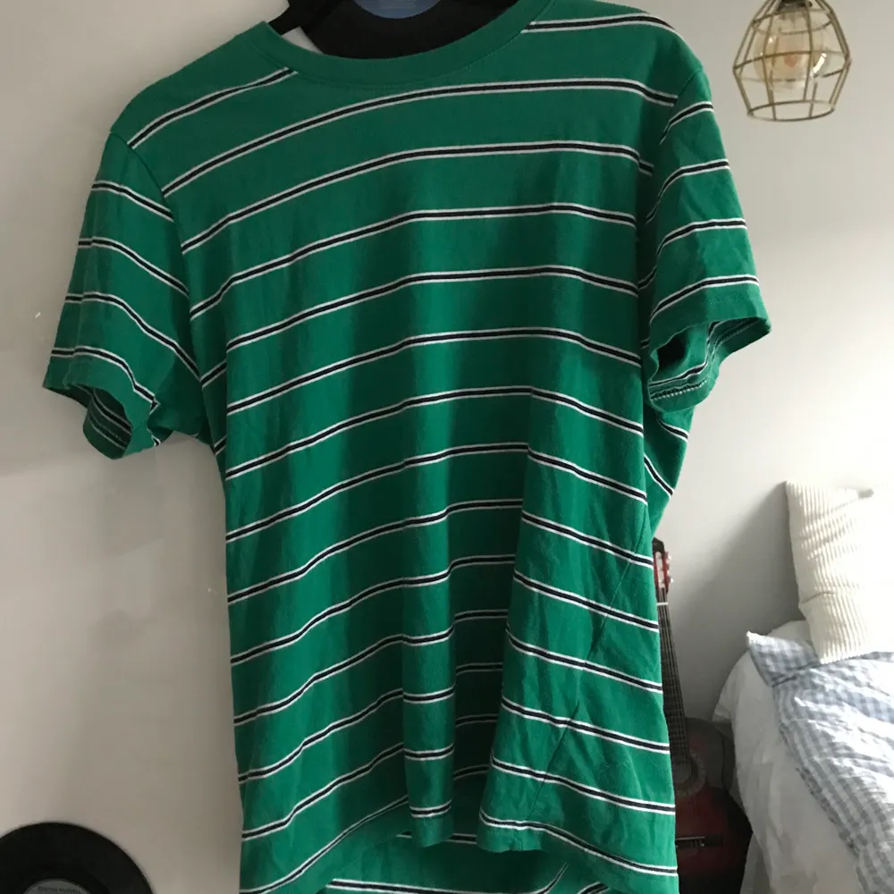En skön grön t-shirt med svarta och vita ränder. . T-shirts.