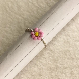Ring - Pris: 30 kr   Färg: ljusrosa, mörk rosa, vit   Material: silvrig ståltråd (ej äkta silver), ljus rosa och gula plast pärlor  Storlek: Omkrets ca  47 mm   Diameter ca 1,7 mm  ❗️Frakt ingår ej❗️ Skriv privat eller kommentera vid köp!💞