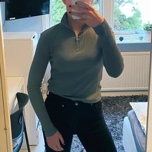 Grön tröja - Grön och skön långärmad tröja, med dragkedja. Man kan alltså välja hur mycket hud man vill visa. Tröjan är ribbad i materialet<33
