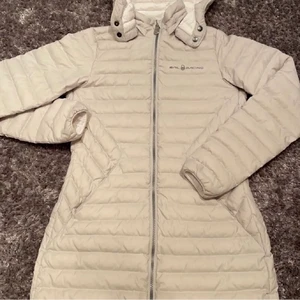 Sail racing dunjacka  - Otroligt fin dunjacka från Sail racing. Figursydd lång jacka som går stax nedanför rumpan. Speciell men fin färg, kritvit på insidan och väldigt ljus grå/vit på utsidan. Säljer pga att jag inte får användning av den då den inte matchar min nuvarande stil. (Sällan använd). Pris 600kr