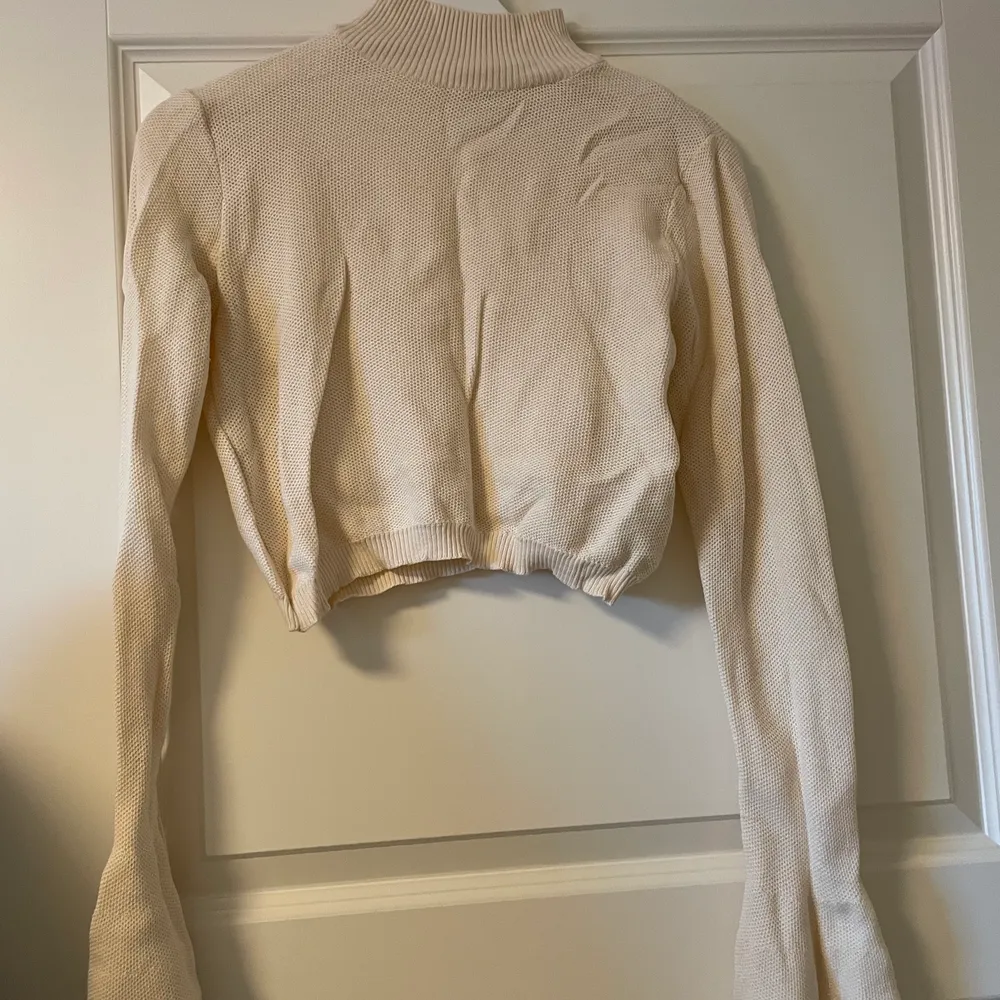 Stickad beige kortare tröja/magtröja från NAKD i storlek S. Använd endast ett fåtal gånger, i princip nyskick,. Stickat.