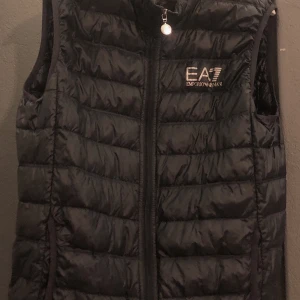 Emporio Armani väst - En mörkblå Armaniväst i Strl L, fint skick överlag men finns ett pyttelitet (som ett knappnålshuvud) hål på (INSIDAN)! Av västen. Annars är dem hur fin som helst.
