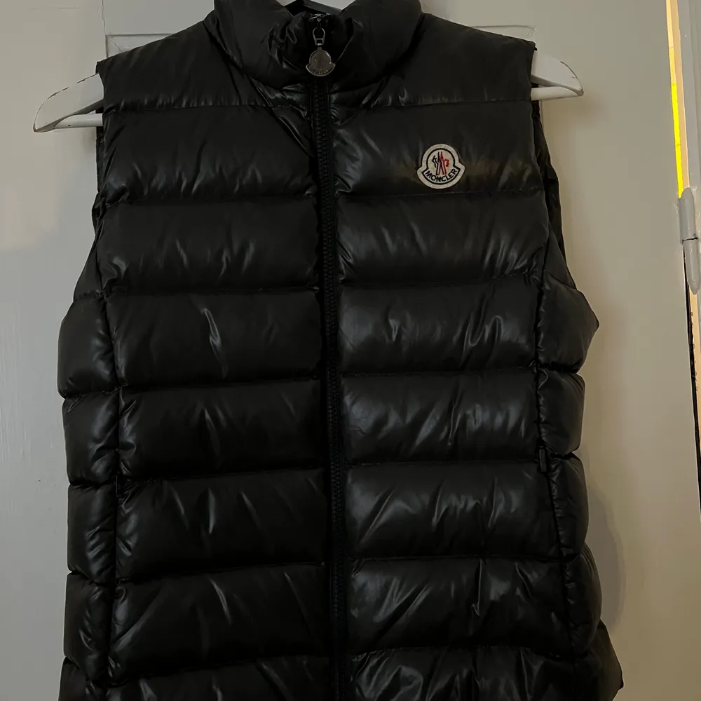 En fin moncler väst i en mörkare grå färg. Övrigt.