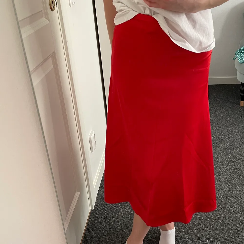 En röd kjol i midi-längd från Nakd. Jättehärlig röd färg. Materialet är silke som är jätteskönt. Endast använd en gång. Dragkedja på sidan. Kan passa flera storlekar i midjan beroende på om man vill ha kjolen högt eller lågt, jag är en xs. . Kjolar.